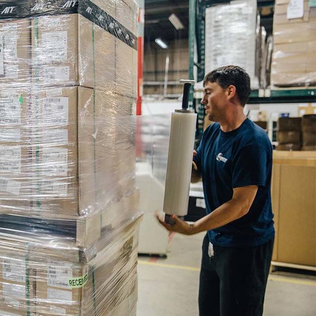 man wrapping shipment boxes